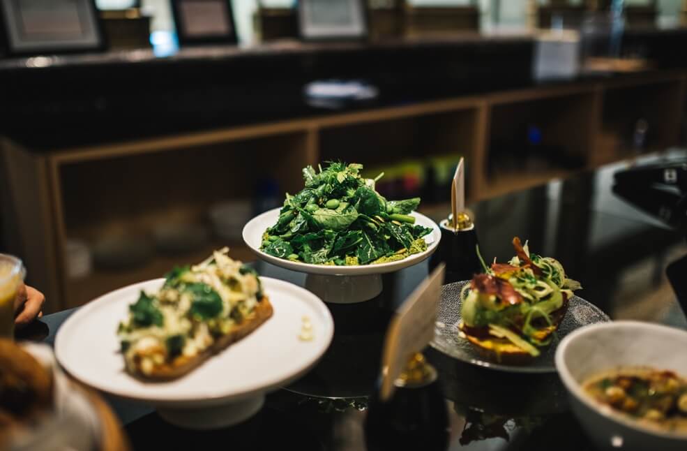 dishes of food on a counter including a spinach salad and a bowl of soup